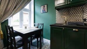A dining area with a table and chairs, a green wall, and a patterned window treatment. - Malila Apartments Cracow Lubicz 14 (Kraków)