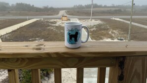 A wooden deck with a white mug featuring a dog silhouette and text. - Doodle Dunes: New! Private Pool + Dog Friendly (Gulf Shores)