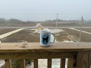 A wooden deck with a white mug featuring a dog silhouette and text. - Doodle Dunes: New! Private Pool + Dog Friendly (Gulf Shores)