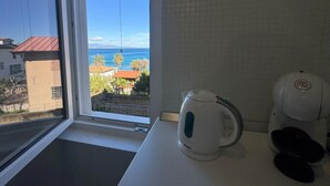 Cuina amb finestra que dona a una vista costanera, una paperena i una cafetera damunt el taulell.