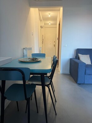 Un salon moderne avec un canapé bleu, une table à manger avec des chaises et un radiateur.