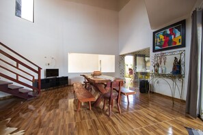 Ein geräumiger Wohnbereich mit Holzboden, einem Esstisch mit Bänken, einer Treppe und einem großen Fenster.