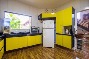 Eine Küche mit gelben Schränken, einem weißen Kühlschrank, einer Mikrowelle und einem Wasserspender.