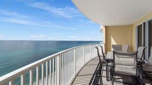 Un balcone con vista sull'oceano, un tavolo con sedie e una finestra.