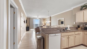 A modern kitchen with a central island, a dishwasher, and a large window providing a view of the outdoors. - Emerald Isle 1808 - Front row chair service included! Affordable rates! (Panama City Beach)