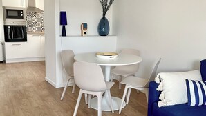 Een moderne woonkamer met een ronde eettafel, witte stoelen, een blauwe bank en een salontafel.