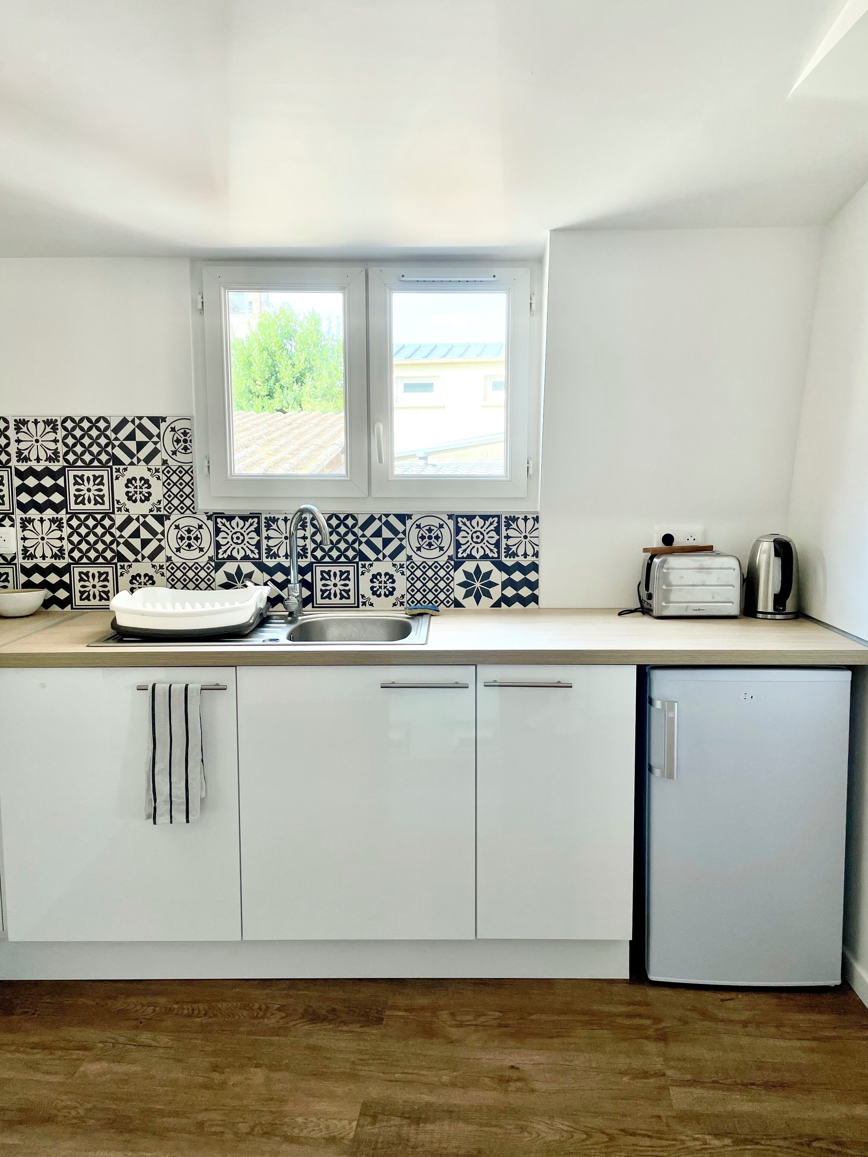 Una cocina moderna con armarios blancos, un fregadero, una ventana y una tostadora sobre la encimera.
