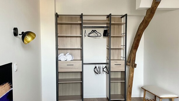 Een moderne slaapkamer met een inbouwkast, nachtkastje en hanglamp.