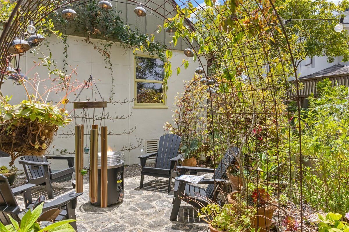 Eine Terrasse mit Sitzgelegenheit, Grill und Garten mit Kletterpflanzen.