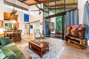 Un salón amplio con un televisor grande, muebles de madera y vistas al exterior.