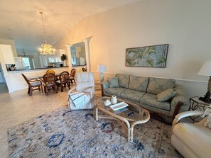 Un salon comprenant un canapé, des fauteuils, une table basse et un coin repas avec des chaises et une table.