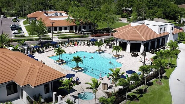 Un resort con piscina central, varias edificaciones con tejados rojos y abundante vegetación circundante.