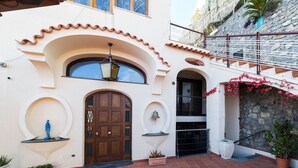 A building with a large wooden door, a balcony with a railing, and a stone wall. - The Shipowner's Villa - your retreat with a view and patio (Campania)