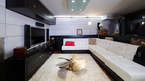 A modern living room with a large flat-screen TV, a white sofa, and a unique sculptural floor lamp. - The Shipowner's Villa - your retreat with a view and patio (Campania)