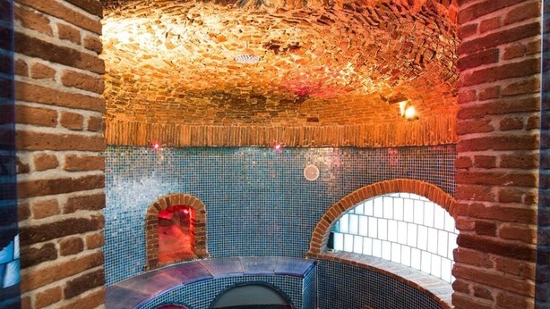 A spa area with a brick archway, a tiled floor, and a circular seating area with a curved bench. - The Shipowner's Villa - your retreat with a view and patio (Campania)