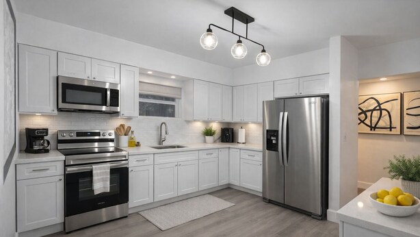 Cocina moderna con armarios blancos, electrodomésticos de acero inoxidable y una isla central con un cuenco de limones.