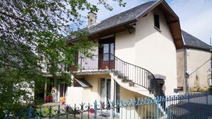 A two-story house with a balcony, a stone pathway, and a blue metal fence. - Calme et détente assurée (Avèze)