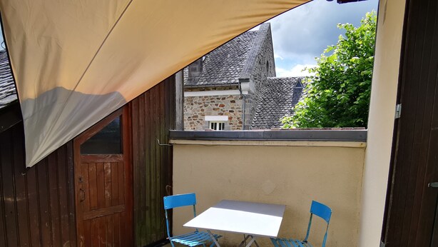 A small outdoor patio with a table and two chairs, a wooden door, and a stone wall. - Calme et détente assurée (Avèze)
