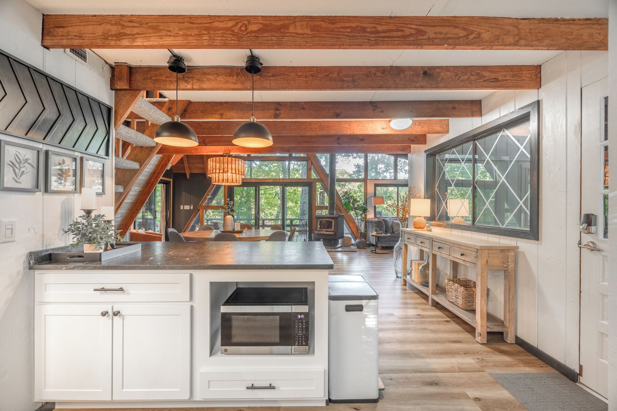 A modern kitchen with white cabinetry, a central island, and a large window providing a view of the outdoors.