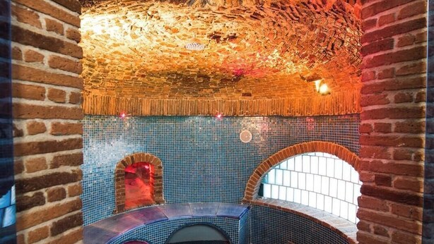 Uma área de spa com parede de tijolos, chão revestido e espaço de estar com um banco curvo.