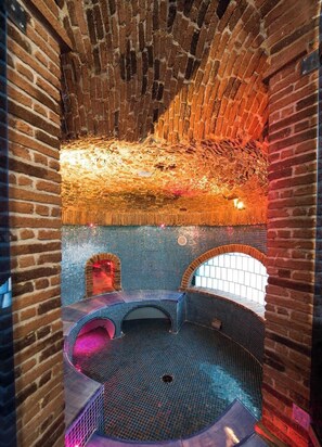A spa area with a brick wall, tiled floor, and a seating area with a curved bench. - Villa Lisuccia - Two Stunning Independent units for your Vacation, with a view (Campania)