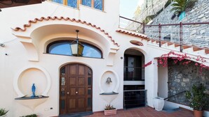 Um edifício com uma grande porta de madeira, uma varanda com guarda-corpo e uma parede de pedra.
