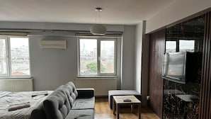 Un salon moderne avec un canapé, une petite table et un téléviseur fixé à un mur de couleur sombre.