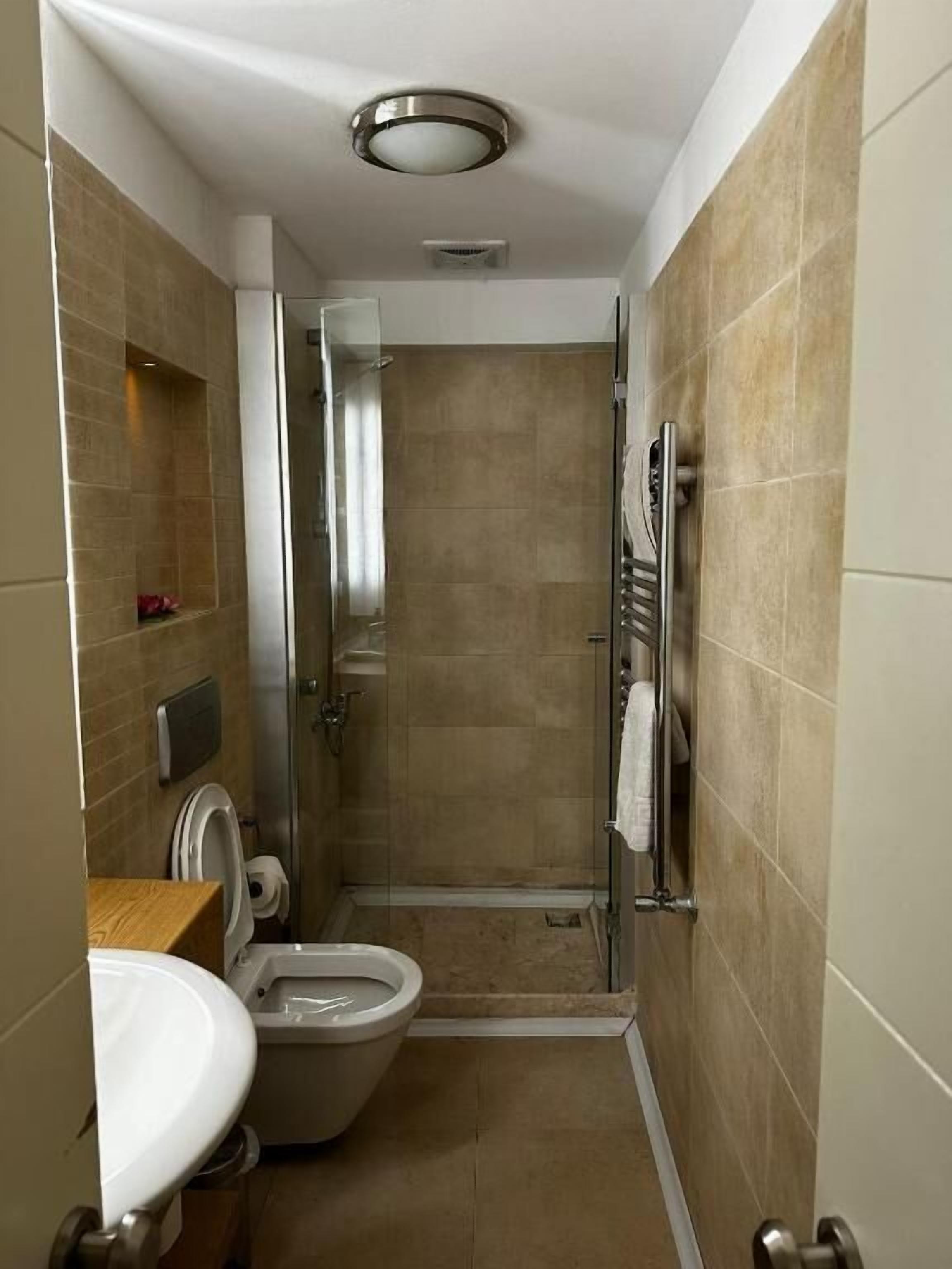 A compact bathroom with a toilet, sink, and shower stall.