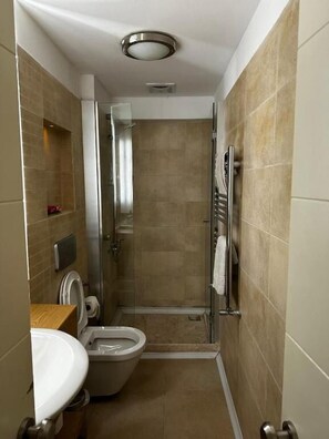 A compact bathroom with a toilet, sink, and shower stall. - D&D PANSİYON (Istanbul)