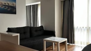 Un salon moderne avec un canapé foncé, une table basse en bois et un tableau accroché au mur.