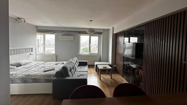 Une chambre à coucher moderne avec un lit, un canapé, une petite table et un téléviseur.