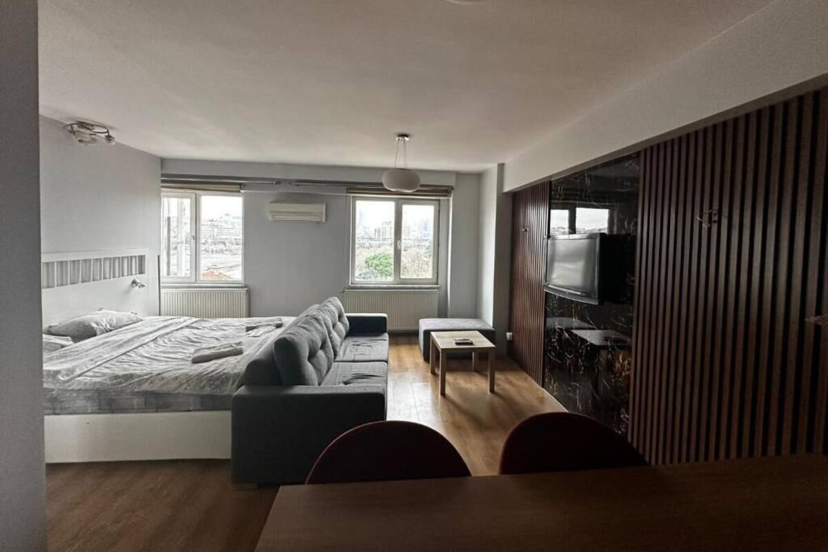 A modern bedroom with a bed, a sofa, a small table, and a TV.