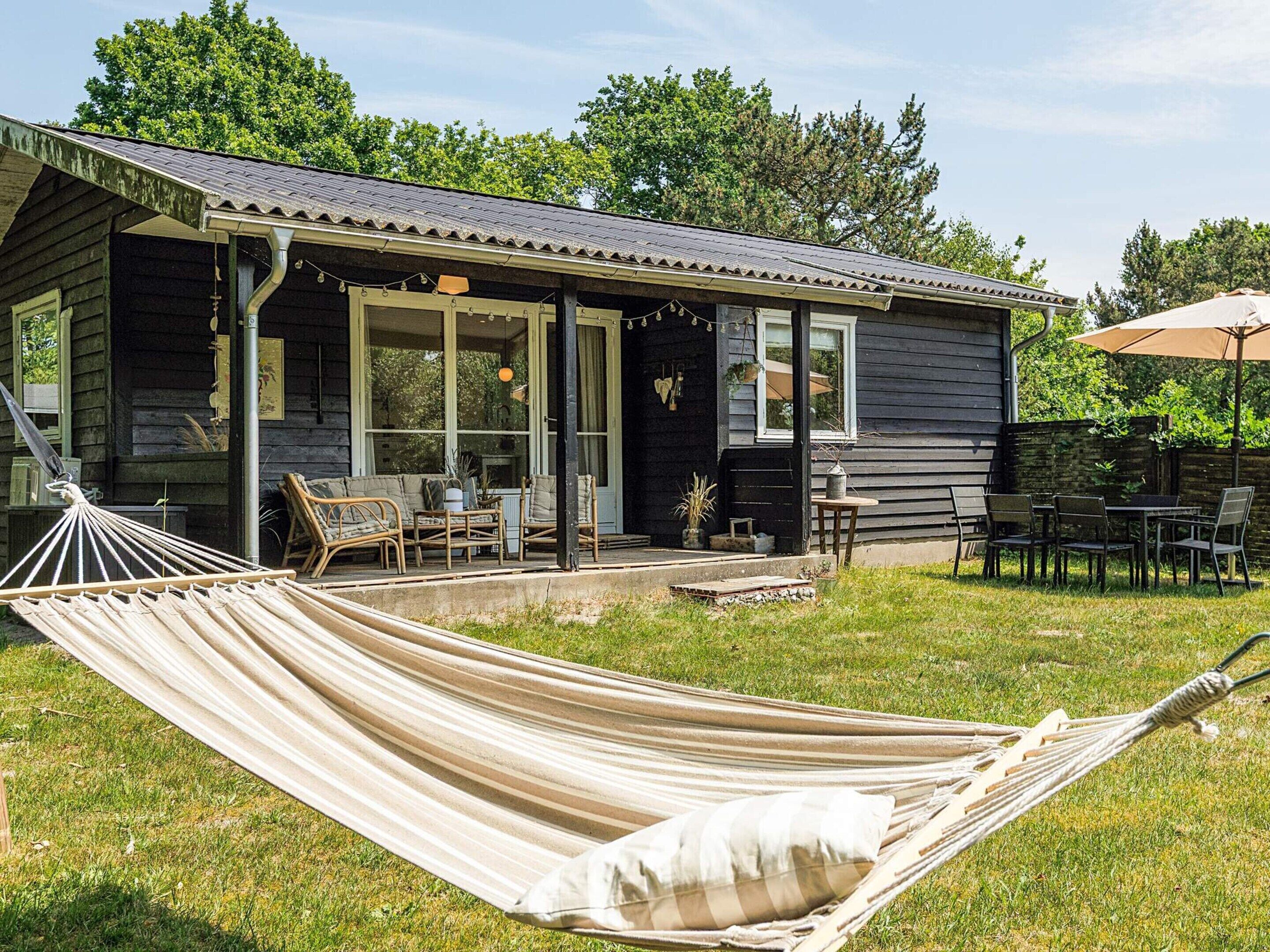 Een houten chalet met een veranda, zitplaatsen buiten en een hangmat.
