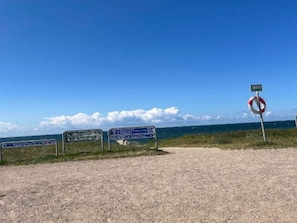 A gravel path leading to beach signs and a lifebuoy. - 5 Person Holiday Home in Rodby (Rodby)