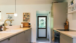 A modern kitchen with two sinks, wooden cabinets, a hanging light fixture, and a view through a door. - 5 Person Holiday Home in Rodby (Rodby)