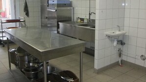 Una cocina comercial con mostradores de acero inoxidable, un lavaplatos y un refrigerador.