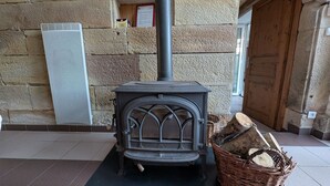 Una pared de piedra con chimenea, una puerta y un cesto de leña.
