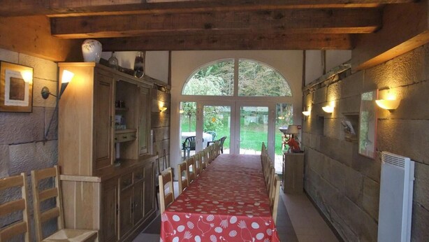 Una larga mesa de comedor con mantel rojo, sillas de madera y techo de madera.