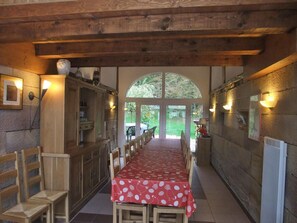 A long dining table with a red tablecloth, wooden chairs, and a wooden ceiling.