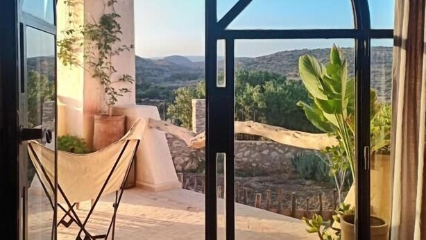 Ein Zimmer mit großem, bogenförmigem Durchgang zu einem Balkon mit Blick auf die Landschaft.