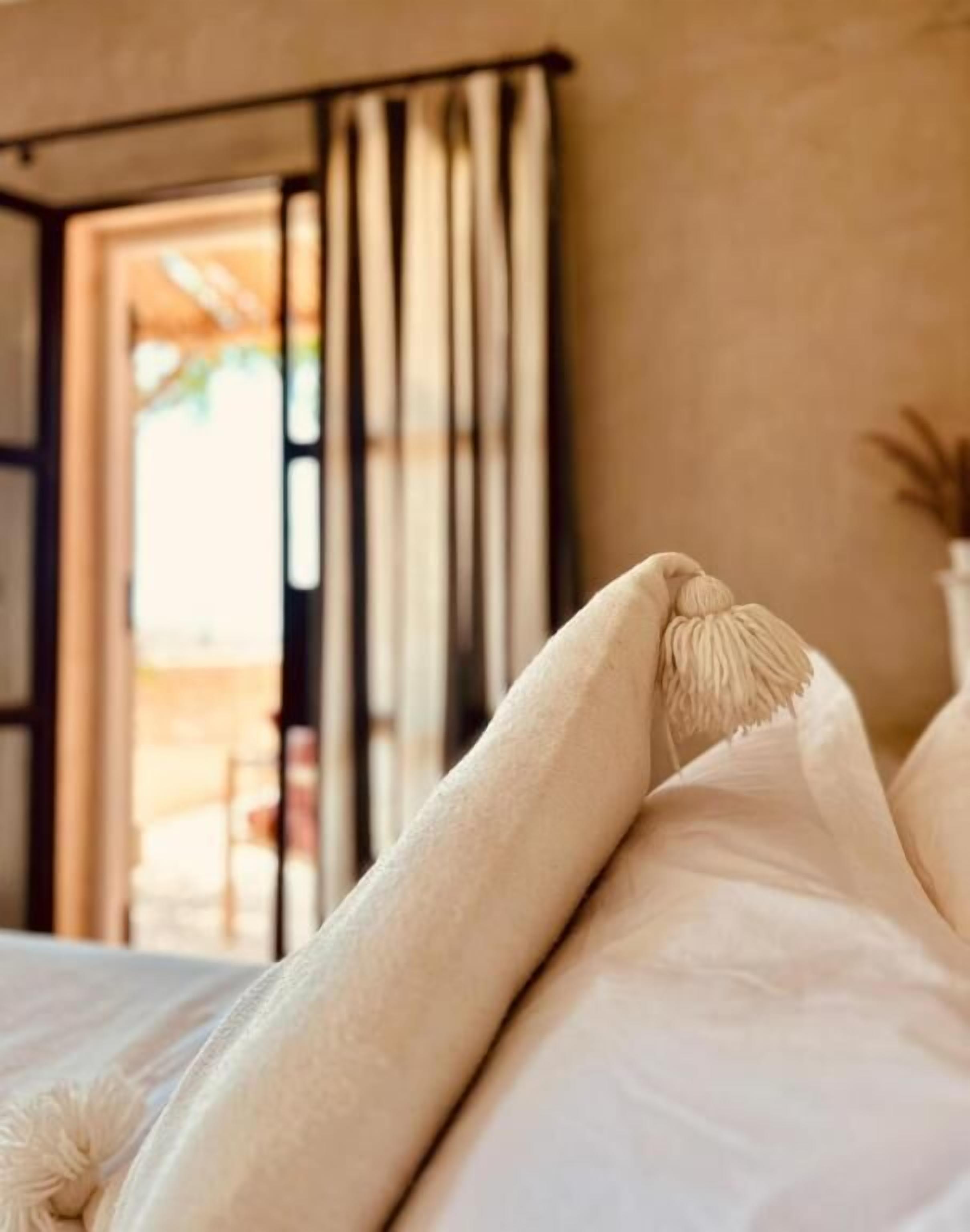 A bed with white bedding and a decorative pillow.