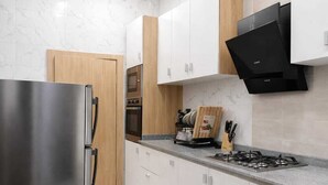 A modern kitchen with stainless steel appliances, white cabinets, and a marble backsplash. - Cozy 2 Bedroom Terrace Duplex + Wi-Fi,TV,24/7 Power In Ajah (Lekki/Ajah)