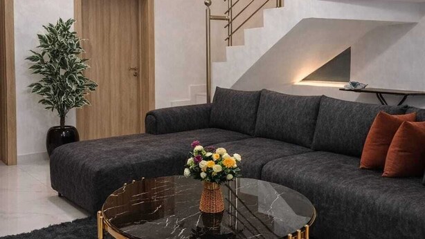 A modern living room with a black marble coffee table, grey sofa, and a staircase with a railing. - Cozy 2 Bedroom Terrace Duplex + Wi-Fi,TV,24/7 Power In Ajah (Lekki/Ajah)