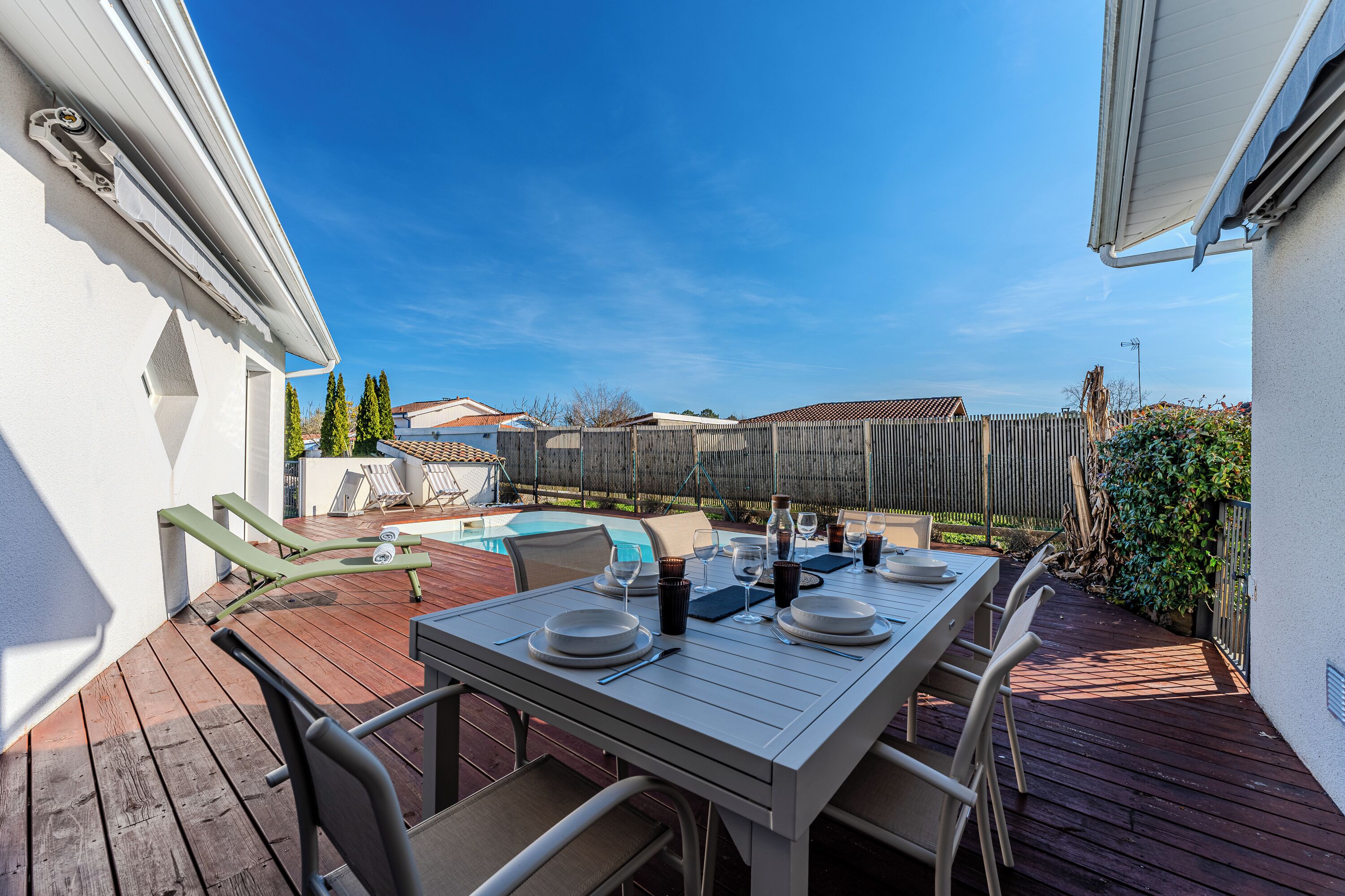 An outdoor patio with a dining table set for four, surrounded by chairs.
