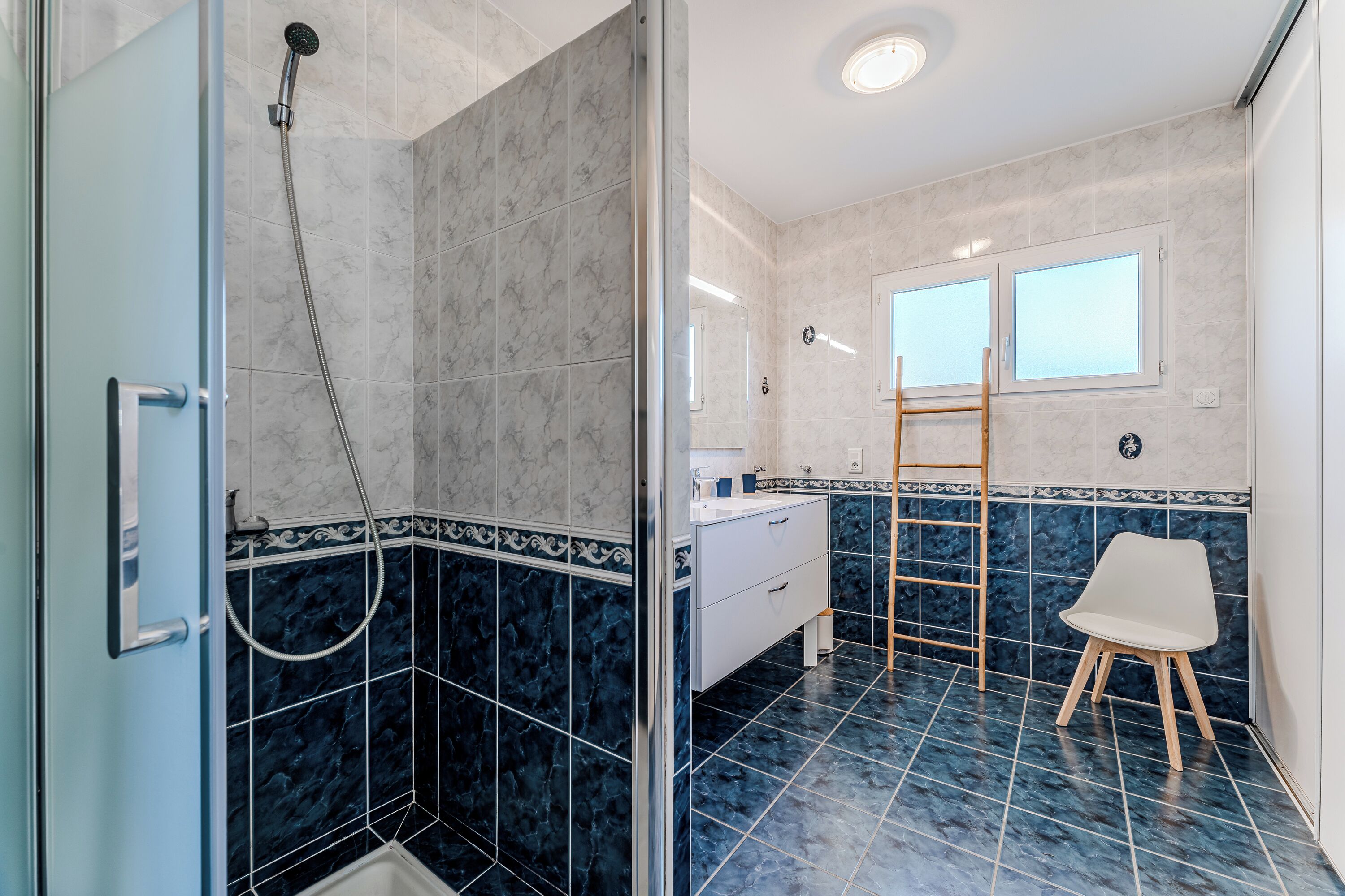 Ein Badezimmer mit Dusche, Toilette, Waschbecken und einem Stuhl.
