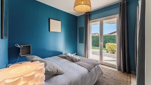 A bedroom with a large bed, a ceiling light, a window with curtains, and a view of the outdoors. - Villa with private pool, garden & wood stove (Le Teich)