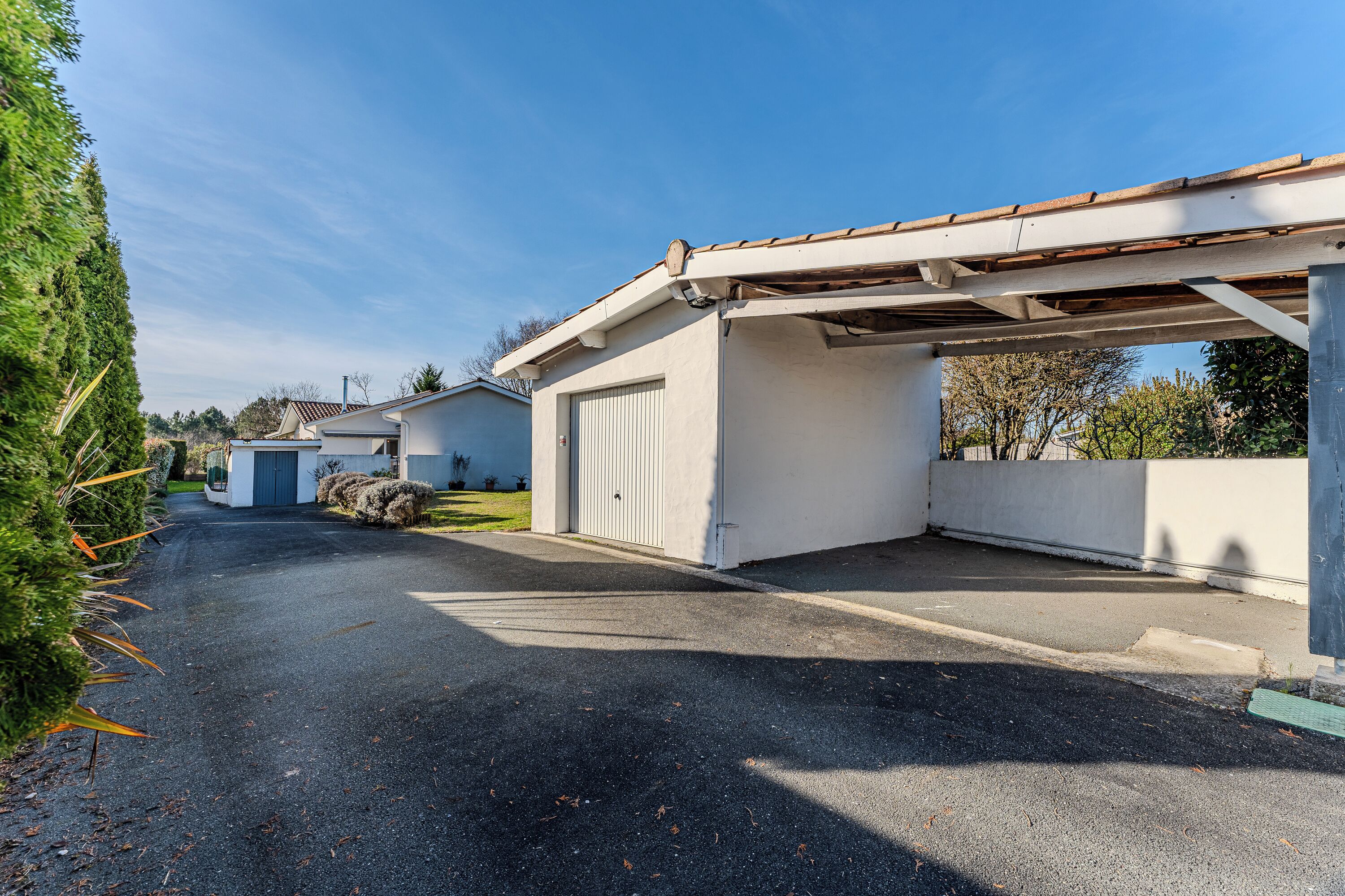 A residential driveway leading to a garage with a covered carport.