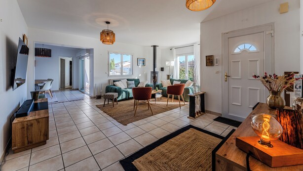 A spacious living room with a large window, a fireplace, and a dining area. - Villa with private pool, garden & wood stove (Le Teich)