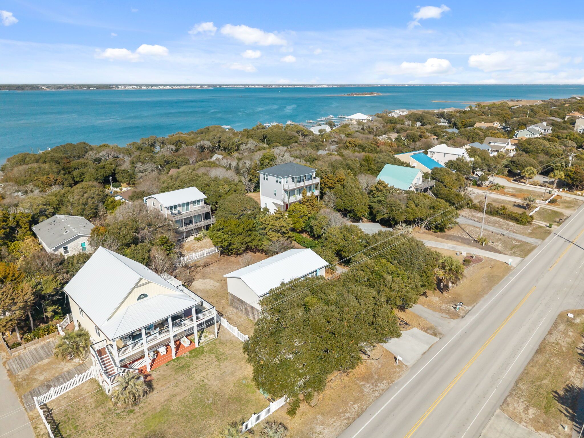 Coastal neighborhood with vacation homes nestled among trees, just steps from pristine turquoise waters and sandy shores.