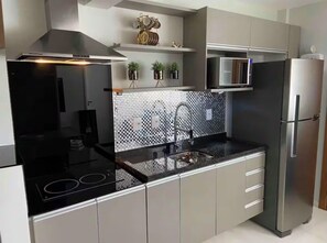 Uma cozinha moderna com fogão preto, eletrodomésticos de aço inoxidável e painel de azulejos.